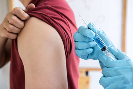 Doctor making injection vaccination patient to prevent pandemic of the disease, flu or influenza virus in clinic.の写真素材