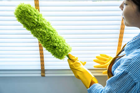 Housekeeping and cleaning concept, Happy young woman in yellow rubber gloves wiping dust using...