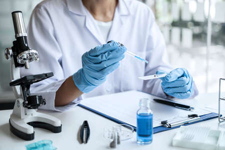 Scientist or medical in lab coat holding test tube with reagent, mixing reagents in glass flask,...