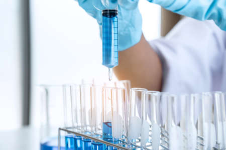Biochemistry laboratory research, Scientist or medical in lab coat holding test tube with using...