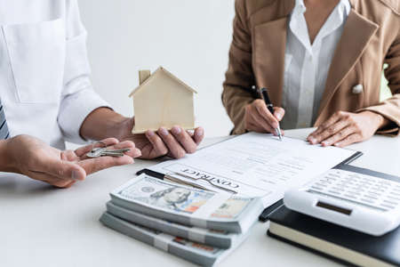 Real estate agent Sales manager holding filing keys to customer after signing rental lease contract...
