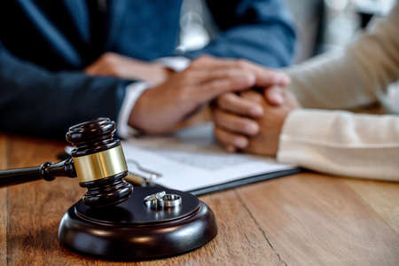 Judge gavel and two golden marriage ring, Contract decree of divorce (dissolution or cancellation) of marriage, husband and wife during divorce process and signing of divorce contract.の写真素材