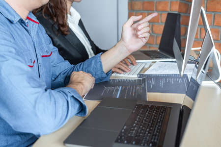 Two professional programmer cooperating and working on web site project in a software developing on desktop computer at company, codes and typing data code, Programming with HTML, PHP and javascript.の写真素材