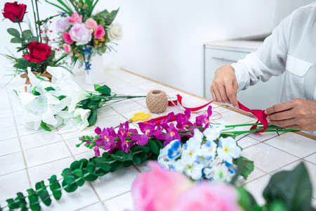 Arranging artificial flowers decoration at home, Young woman florist work making organizing diy artificial flower, craft and hand made concept.の写真素材
