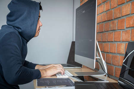Computer hacker or cyber attack concept, Dangerous hooded hacker using multiple computers typing bad...