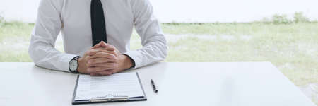 Interviewer or Board reading a resume during a job interview, Employer interviewing a young male job seeker for recruitment talking in modern office, employment and recruitment concept.の写真素材