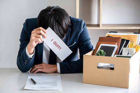 Images of packing up all his personal belongings and files into a brown cardboard box, Businessman...