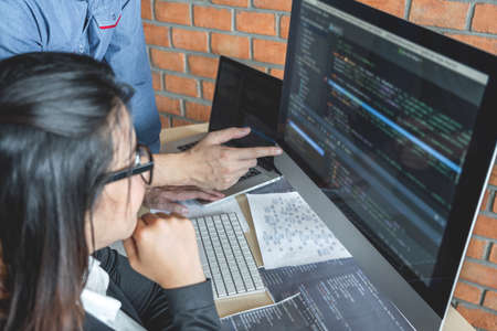 Programmers cooperating at Developing programming and website working in a software develop company office, writing codes and typing data code, Programming with HTML, PHP and javascript.の写真素材