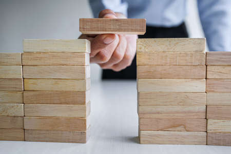 Plan and strategy in business, Risk To Make Business Growth Concept With Wooden Blocks, hand of man has piling up and stacking a wooden block.の写真素材