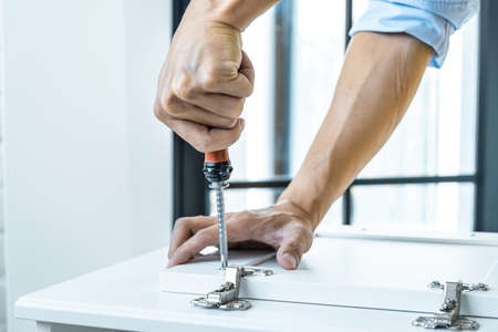Man doing renovation work at home with screwdriver drill wood nail installation on locker.の写真素材