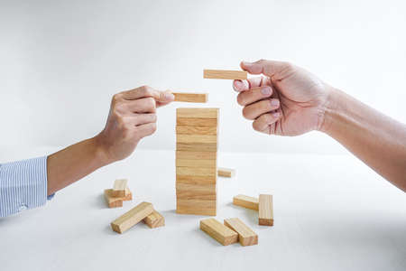 Plan and strategy in business, Risk To Make Business Growth Concept With Wooden Blocks, hand of man has piling up and stacking a wooden block.の写真素材