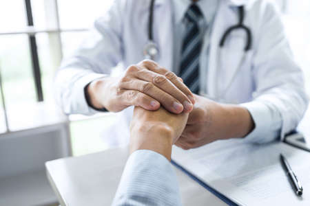Doctor touching patient hand for encouragement and empathy on the hospital, cheering and support patient.の写真素材