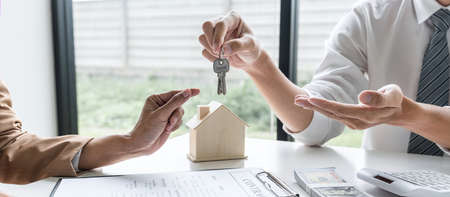 Estate agent giving house keys to client after signing rental lease contract of sale purchase...