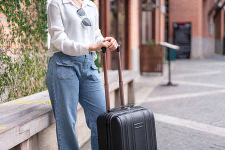 Woman traveller standing and dragging black suitcase luggage walking to passenger boarding in airport, Travel concept.の写真素材