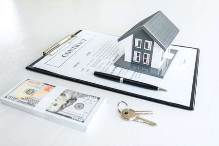 House model and Money, house key lying on real estate contract, home loan and investment concept.の写真素材