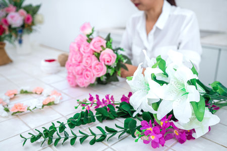 Arranging artificial flowers decoration at home, Young woman florist work making organizing diy artificial flower, craft and hand made concept.の写真素材