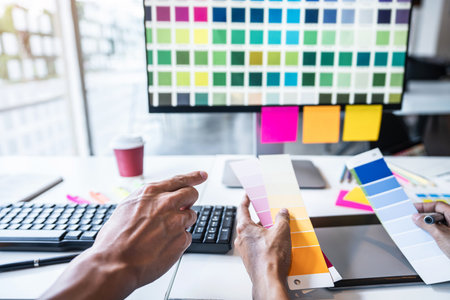 Young colleagues designers working together on a creative project and color samples for selection, Color swatch samples, Brainstorming Planning Partnership, creative graphic design working desktop.の写真素材
