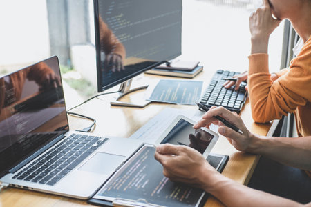 Programmers cooperating at Developing programming and website working in a software develop company office, writing codes and typing data code, Programming with HTML, PHP and javascript.の写真素材