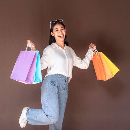 Portrait of Asian girl excited beautiful girl wearing sunglasses happy smiling with holding shopping bags enjoying in shopping relaxed expression, Positive emotions shopping, lifestyle concept.の写真素材