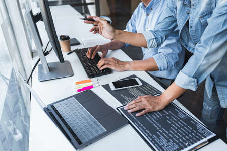 Writing codes and typing data code technology, Programmer cooperating working on web site project in...