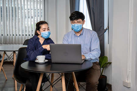 Young asian business couple looking business data on laptop to brainstorming new project while...
