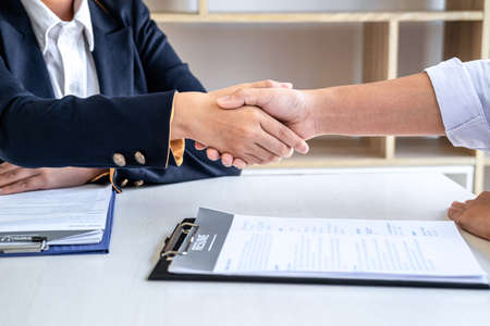 Greeting new colleagues, Handshake while job interviewing, Female candidate shaking hands with Interviewer or employer after a job interview, employment and recruitment concept.の写真素材