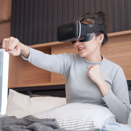 Close up of young asian woman in casual clothes wearing virtual reality glasses to playing fight in...