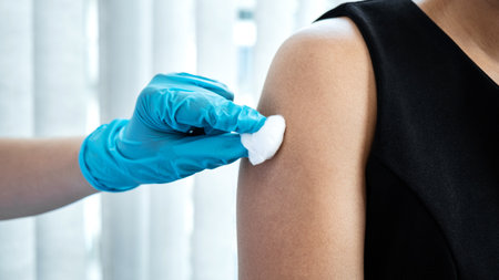 Doctor in medical glove holding syringe and using cotton before injection coronavirus vaccine in shoulder of patient to protection from covid-19 pandemic during doctor made an appointment at hospitalの写真素材