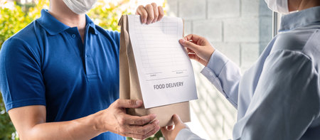 Asian delivery man showing grocery bag and food delivery bill to customer to sending product in...