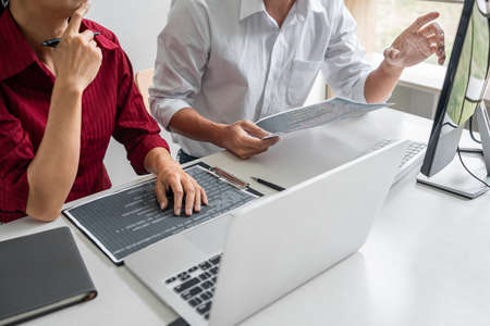 Two professional programmer cooperating and working on web site project in a software developing on desktop computer at company, codes and typing data code, Programming with HTML, PHP and javascript.の写真素材