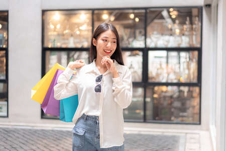 Portrait of Asian girl excited beautiful girl happy smiling with holding shopping bags relaxed expression, Positive emotions shopping, lifestyle concept.の写真素材