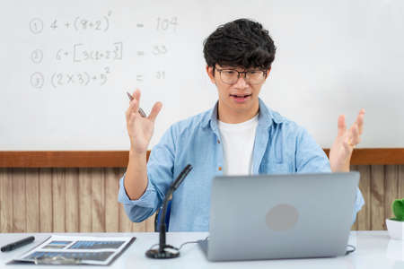 Male tutor using laptop and though camera to teaching new lesson by video conference on webcam while...