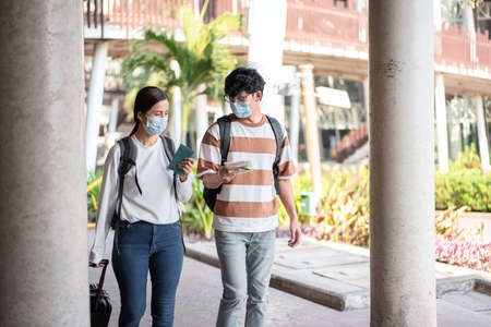 Tourist couple are talking and walking with luggage and passport on the street go to the airport together in vacation time with new normal lifestyle during covid-19 outbreakの写真素材