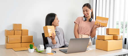 Asian woman colleague is preparing packing products in parcel boxes for delivery to client after...