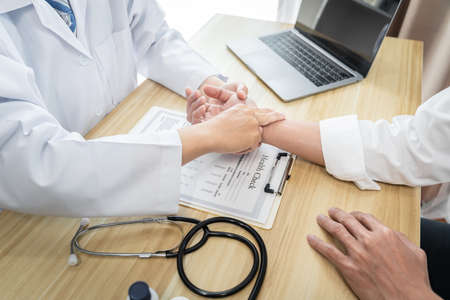 Doctor in white coat taking and checking the patient's wrist pulse during the examination diagnosis...
