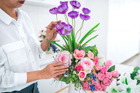 Arranging artificial flowers decoration at home, Young woman florist work making organizing diy artificial flower, craft and hand made concept.の写真素材