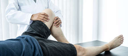 Male patient lying on the bed to getting healing treatment and rehabilitation injured knee and legs...