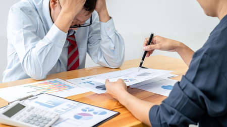 Male employee is holding his head with feeling stress about unsuccessful project after executive...