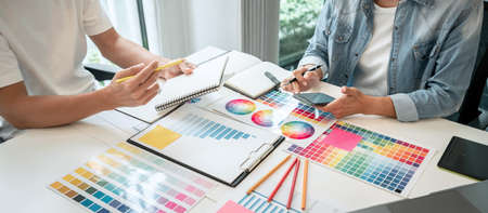 Two creative graphic designer working on color selection and drawing on graphics tablet at...