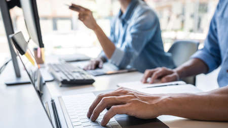 Writing codes and typing data code technology, Programmer cooperating working on web site project in...