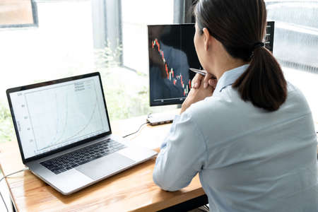 Businesswoman investor having planning a new project and analyzing graph data with display screen the data presented and deal on a stock exchange.の写真素材