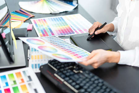 Young creative graphic designer working on color selection and drawing on graphics tablet at...