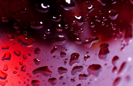 Macro close up of side of wine glass with red or rose wine covered with droplets of waterの写真素材