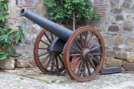 Antique cast iron Canon with spoked wheels in a castle courtyard in Spain