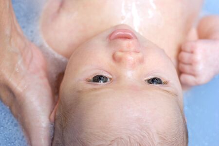 Baby girl having her first bath at home and smiling at her mother