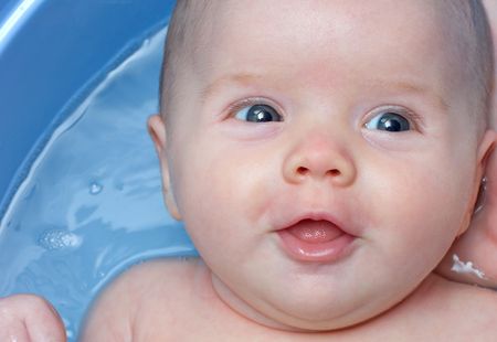 Baby girl having her first bath at home and smiling at her mother