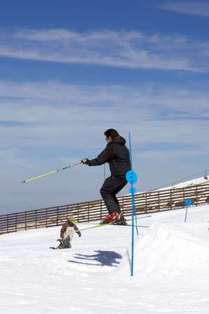 Snowy ski slopes of Prodollano ski resort in the Sierra Nevada mountains in Spain with man making a jumpの写真素材