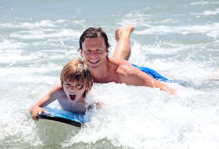 Young father and son happily learning to surf whilst on vacation in sunny Spain