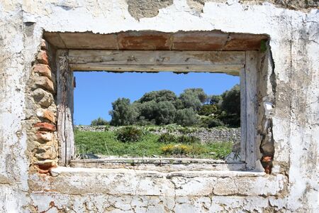 Pretty Spanish countryside seen through hole in wall of old run down ruinsの写真素材