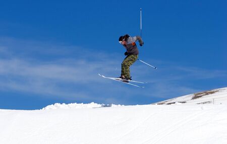 Snowy ski slopes of Prodollano ski resort in the Sierra Nevada mountains in Spain with skier making a big jumpの写真素材